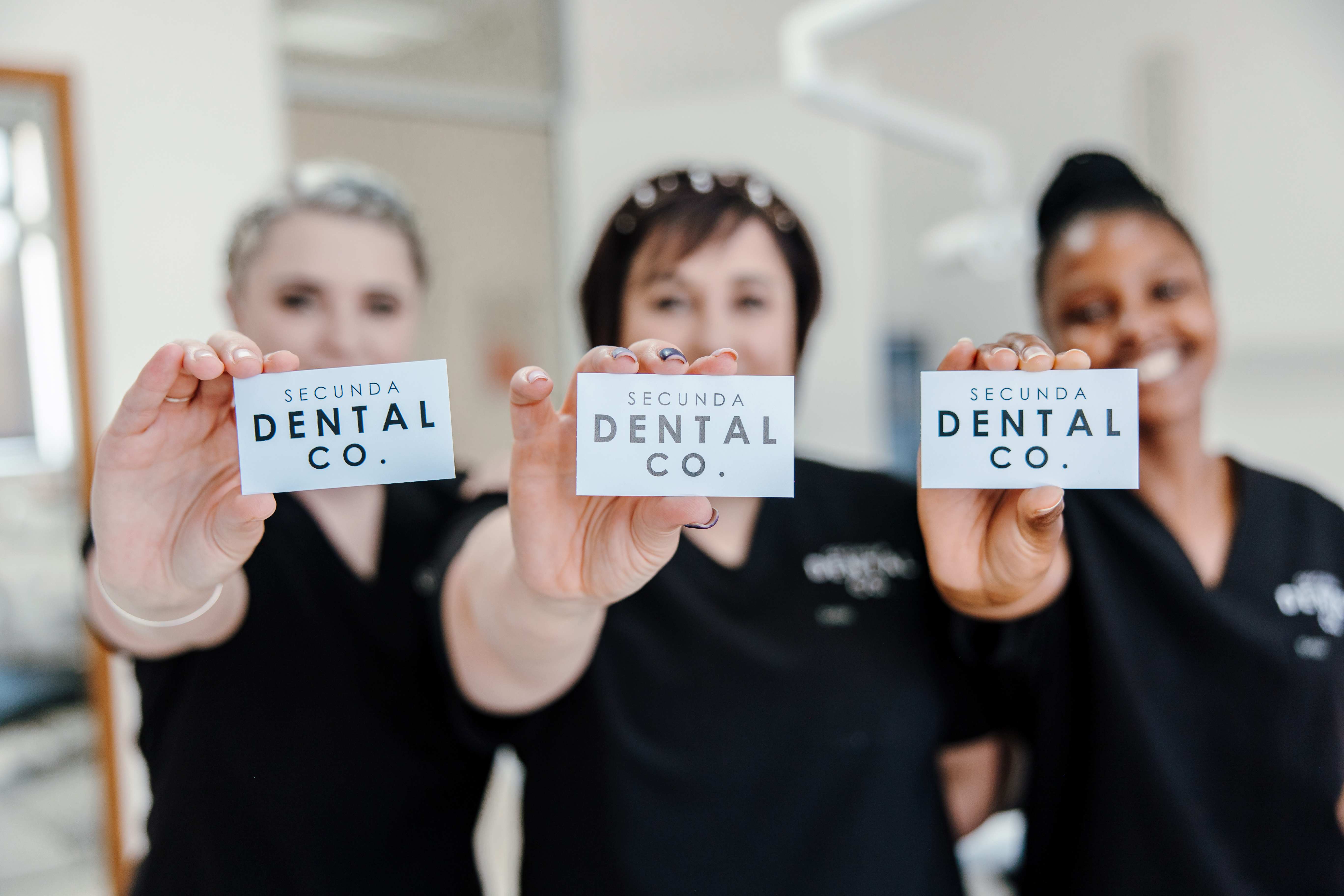 Team members holding Secunda Dental Co. business cards